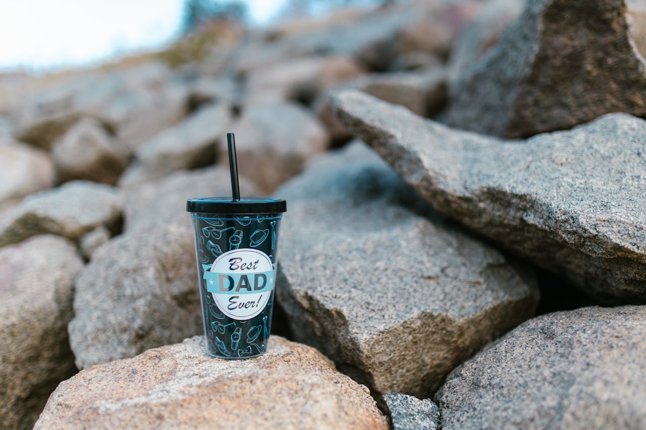 A disposable cup with Best Dad Ever! on rocky terrain, symbolizing appreciation.